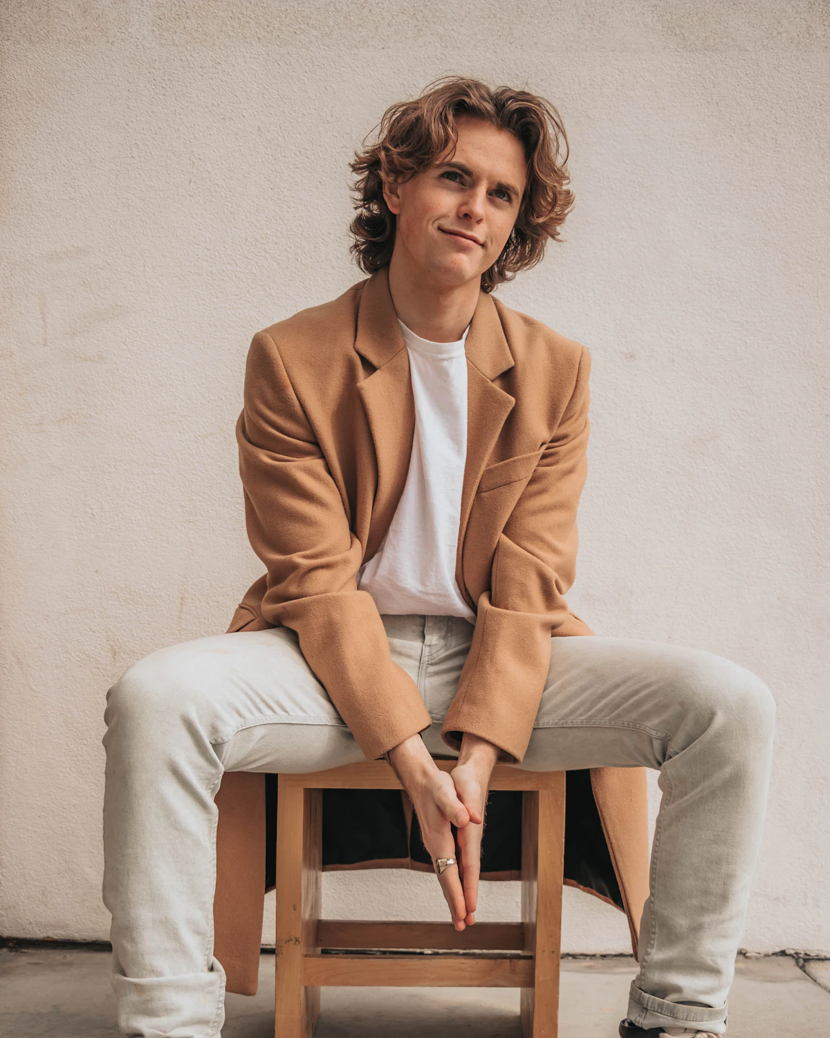 Homme assis portant un manteau camel